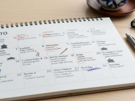 Open calendar marked with handwritten notes for temple visits and neighborhood walks during a week in Kyoto