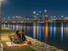 Han River at night with city skyline in background with locals sitting around 