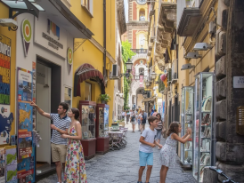 Cobblestone street lined with colorful Italian storefronts