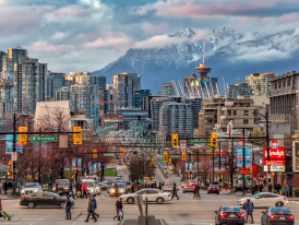 Street view of a busy Vancouver street with mountains in the distance
