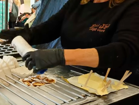 Poffertjes griddle at Noordermarkt, vendor dusting mini pancakes with powdered sugar