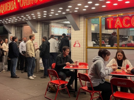 Roma Norte side street at night with warm taquería lights and people eating