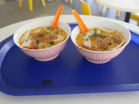 A steaming bowl of laksa with cockles
