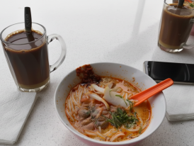 A steaming bowl of laksa with cockles