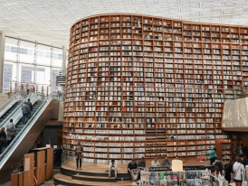 Multi-level bookstore interior with floor-to-ceiling shelves and Korean readers