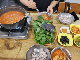 Steaming bowls of kimchi jjigae with full banchan spread