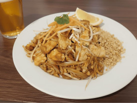 Plate of pad thai with lime wedges and crushed peanuts