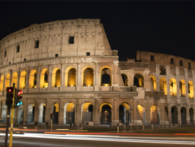 Colosseum illuminated at night with amber lighting against a dark sky