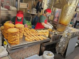 Vendor flipping golden mung bean pancakes at Gwangjang Market