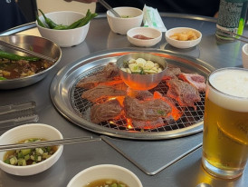 Charcoal galbi grilling on a dome grill with smoke rising
