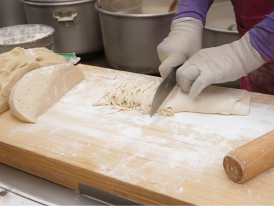 Kalguksu noodles being hand-cut into a steaming pot