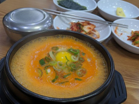 Bubbling sundubu jjigae with raw egg and seaweed flakes
