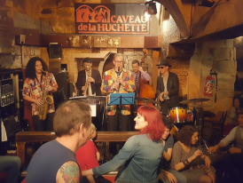 Intimate jazz club basement with a musicians performing for a small crowd