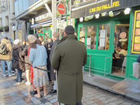 A vibrant Parisian street scene in the Marais district with falafel lines