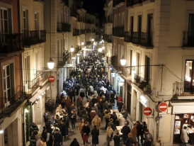 Crowds spilling onto narrow Bairro Alto streets with open bar doors at dusk