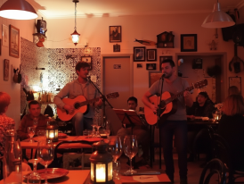 Fado singer eyes closed mid-performance in candlelit Alfama tavern
