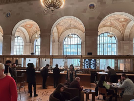 People enjoying baked goods and coffee under soaring ceilings in a historic space