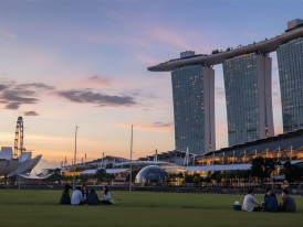 Marina Bay waterfront at golden hour with locals on grass and Marina Bay Sands skyline