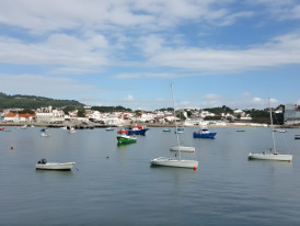 Fishing boats docked at Cascais marina with pastel buildings behind