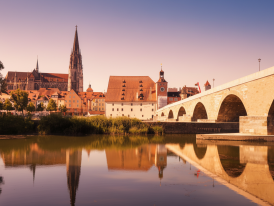 Stone bridge in Regensburg with cathedral at golden hour
