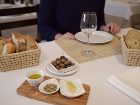 Basket of crusty bread with small bowl of olive oil on a café table
