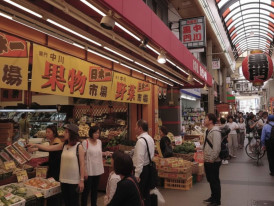 Covered Japanese market street with locals shopping for fresh produce
