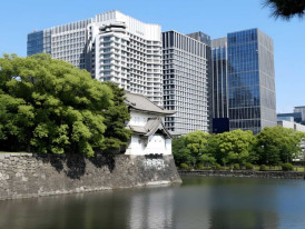 Stone walls and moat of the Imperial Palace East Gardens with modern Tokyo buildings beyond