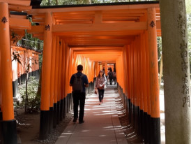 Visitors walking through vermilion torii gates at Fushimi Inari Shrine, Kyoto