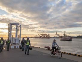 Dock workers and cyclists along Minato Harbor at sunset