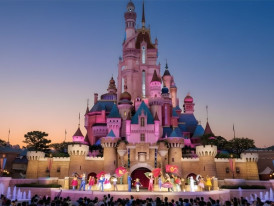 Hong Kong Disneyland’s fairytale castle illuminated in pink at dusk