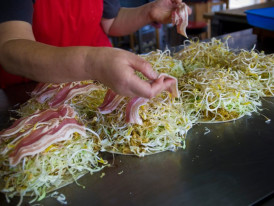 Hiroshima-style okonomiyaki cooking on a teppan grill