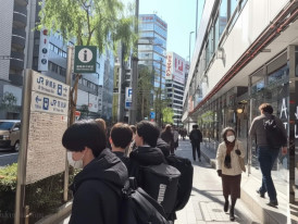 People walking along a busy Tokyo street with Japanese signage