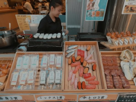 Sushi and seafood street food stall at Tsukiji Outer Market in Tokyo, with fresh nigiri and skewered snacks on display