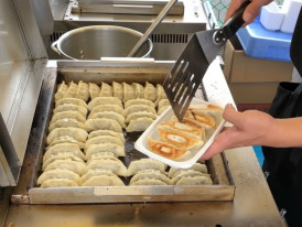 Pan-fried gyoza dumplings being cooked on a flat grill at a Tokyo street food stall
