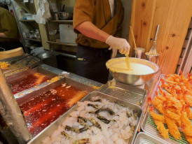 Fresh shrimp tempura being battered and fried at a Tokyo street food stall
