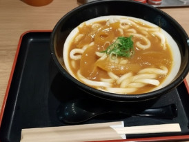 Bowl of Japanese udon noodles in savory broth served on a tray at a casual Tokyo eatery