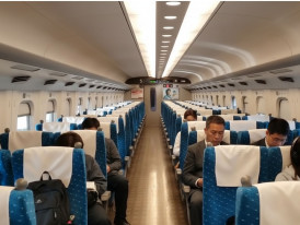 Interior of a Shinkansen bullet train with reserved seating and passengers traveling between major Japanese cities