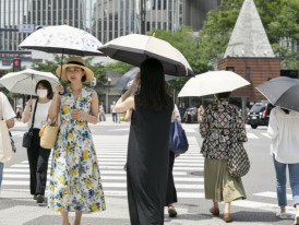 Pedestrians in Japan using umbrellas on a hot summer day, showing how locals manage heat, humidity, and seasonal weather