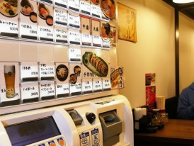 Japanese restaurant ticket vending machine with menu buttons and prices, showing how customers order meals before seating