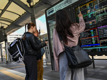 People looking at a bus sign board in Kyoto, Japan
