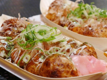 Takoyaki at street food close up in tradional wooden boat. Takoyaki at street food close up in tradional wooden boat.