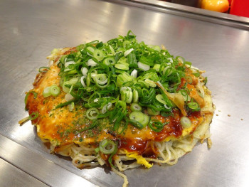 Chef preparing okonomiyaki with generous green onions. Chef preparing okonomiyaki with generous green onions.