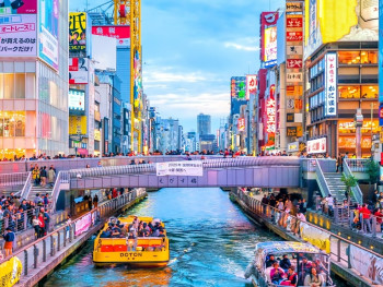 Dotonbori canal during daytime with traditional storefronts reflected in the water. Dotonbori canal during daytime with traditional storefronts reflected in the water.