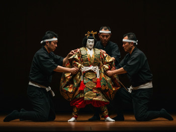 Three master puppeteers in traditional black clothing manipulating an ornate bunraku puppet on stage at the National Bunraku Theater. Three master puppeteers in traditional black clothing manipulating an ornate bunraku puppet on stage at the National Bunraku Theater.