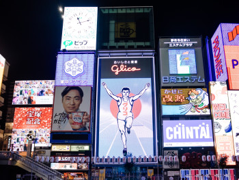 Iconic Glico running man sign reflecting in Dotonbori canal at night. Iconic Glico running man sign reflecting in Dotonbori canal at night.