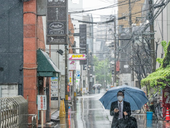 Local businessman with umbrella navigating flooded Osaka sidewalk during heavy rain Photo by Hugo Sykes on pexels