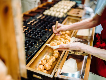 Hands picking up Takoyaki from vendor. Hands picking up Takoyaki from vendor.