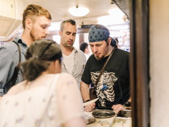 Host explaining dishes to attentive guests Host explaining dishes to attentive guests