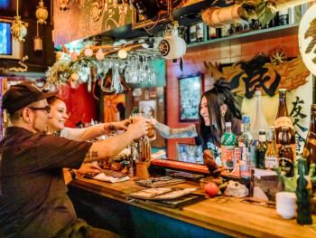 Guests clinking drinks at an izakaya with host smiling Guests clinking drinks at an izakaya with host smiling