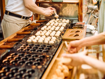 Takoyaki being flipped at street food stall Takoyaki being flipped at street food stall